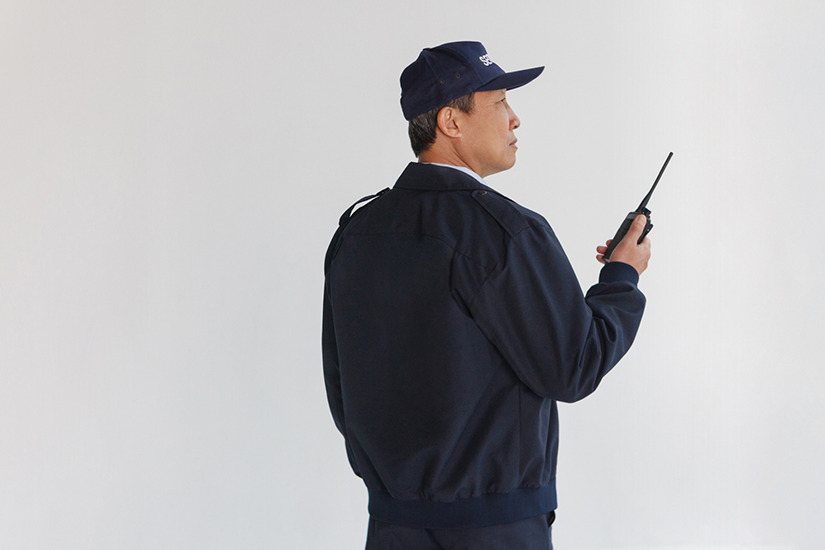 無線機を持った警備員の後ろ姿の画像