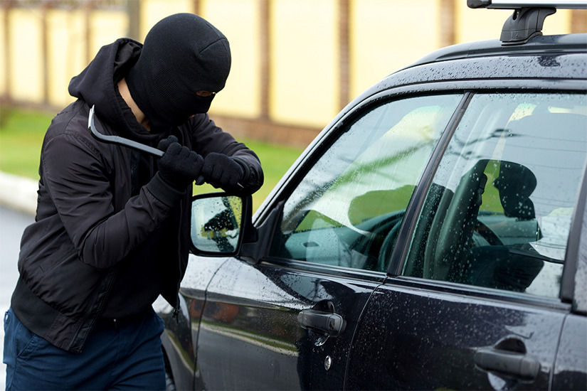 自動車の窓ガラスを割り、車上荒らしを行おうとしている男の画像