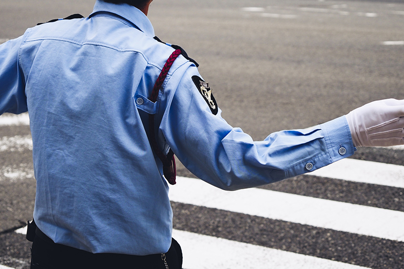 横断歩道前で交通整理をする警察官の写真
