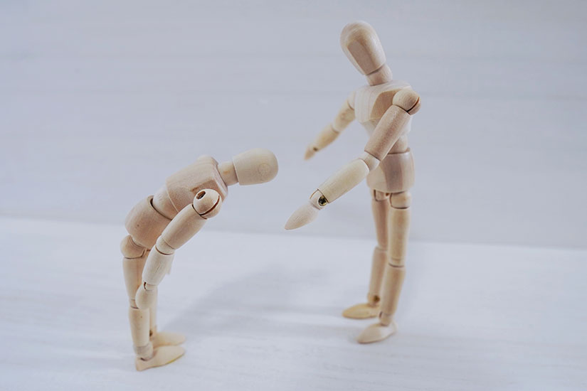 怒っている人形と、謝罪している人形が向き合っている様子